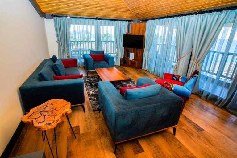 Amplio salón con sofás azules y suelo de madera en Porto Amore Club Hotel con vistas al exterior