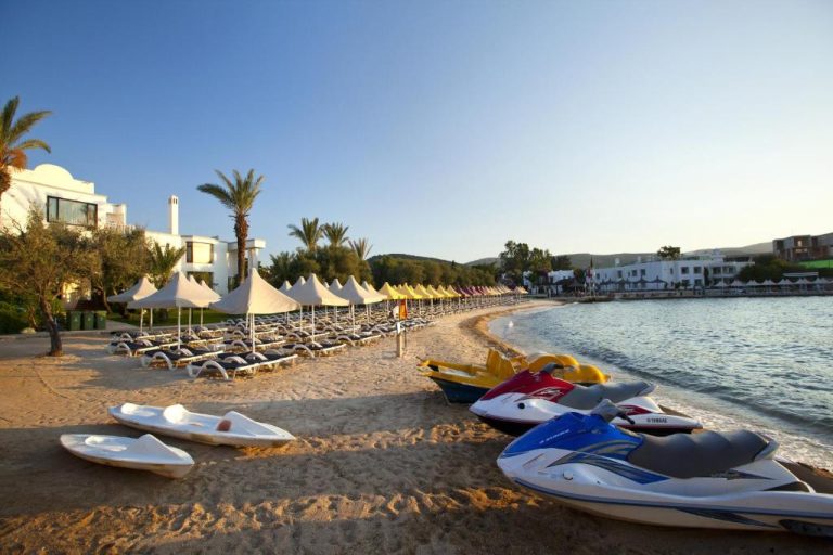 Playa privada con motos de agua y tumbonas bajo sombrillas del Samara Hotel Bodrum Ultra All Inclusive