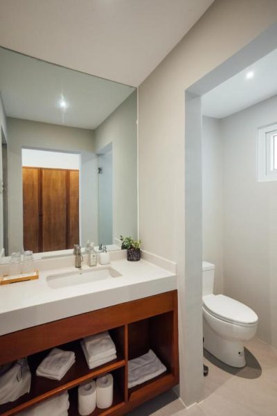 Baño moderno con lavabo empotrado, espejo grande y zona de inodoro independiente en Solitude Acacia Resort