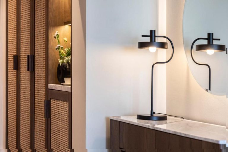 Armario de ratán y lámpara de diseño negro sobre consola de mármol en Kerkyra Blue Hotel & Spa