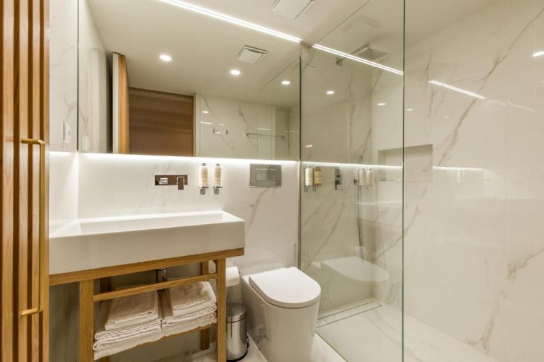 Baño de mármol blanco con ducha acristalada y lavabo moderno en Ribeira Douro Hotel