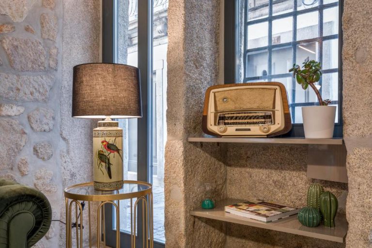 Salón vintage con radio antigua, lámpara decorativa y estantería de piedra en Ribeira Douro Hotel