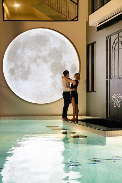 Pareja romántica junto a la piscina interior con decoración de luna del Ratri Hotel Phuket Old Town