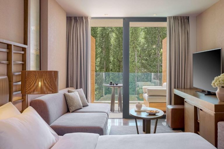 Sala de estar moderna con terraza y vistas al jardín en Angsana Corfu Resort & Spa