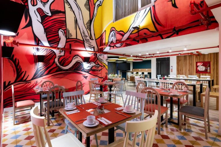 Restaurante del Hotel Vilar América con colorido mural pop art en rojo y amarillo y mesas preparadas