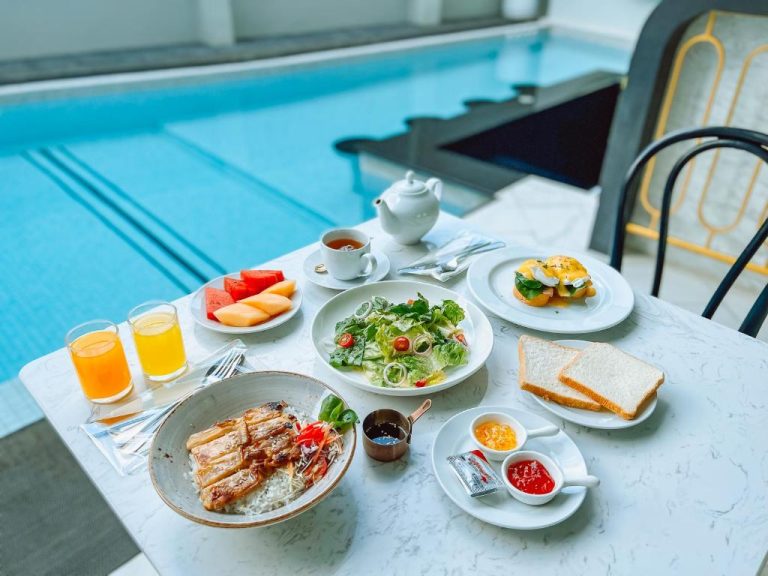 Desayuno completo junto a la piscina del Ratri Hotel Phuket Old Town con frutas, ensalada y zumos