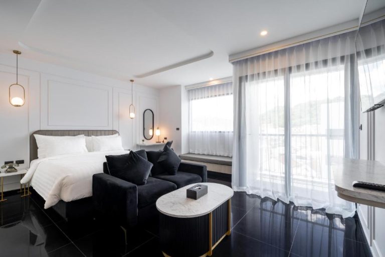 Suite de lujo con cama doble y sofá negro en Ratri Hotel Phuket Old Town con balcón
