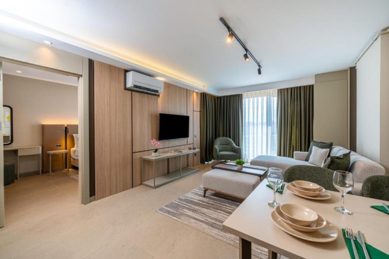 Amplio salón comedor moderno con televisión y sofá en las suites del hotel Casamax Suites
