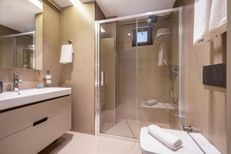 Baño moderno con ducha de mampara de cristal y lavabo empotrado en Casamax Suites