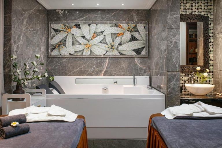Suite de spa con jacuzzi, camillas de masaje y mosaico floral en Lucien Hanoi Lakeside Hotel