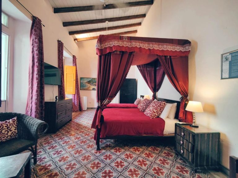 Habitación colonial con cama de dosel roja y suelo hidráulico en Hotel Boutique Casa Sánchez