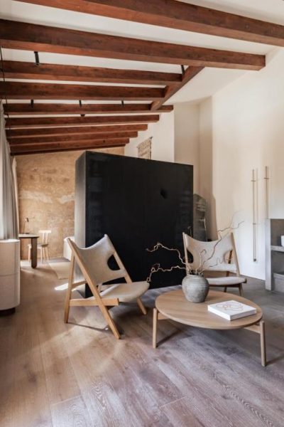 Salón con vigas de madera y chimenea negra en Nobis Hotel Palma, Design Hotels