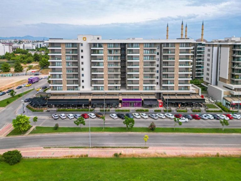 Vista aérea de la fachada exterior del Casamax Suites con aparcamiento y mezquita al fondo