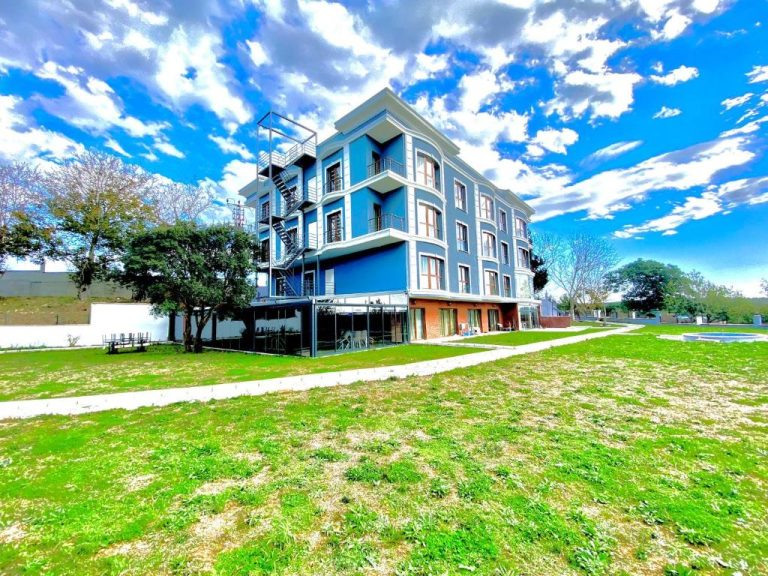 Fachada exterior azul del Green Roof Boutique Hotel & SPA Istanbul Airport con jardín y cielo despejado