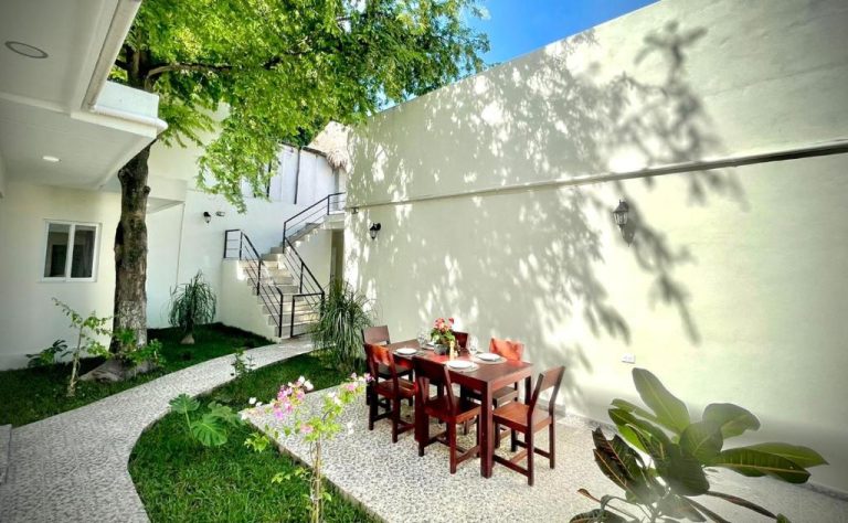 Terraza exterior con mesa de comedor y jardín tropical en Casa Creunza de Mar