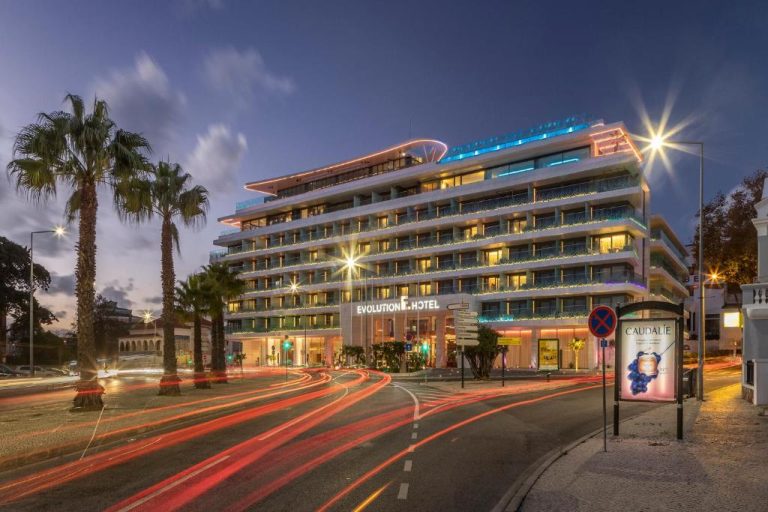 Fachada exterior iluminada del EVOLUTION Cascais-Estoril Hotel de noche con palmeras