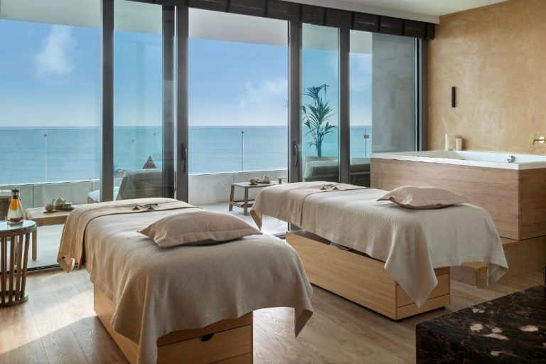 Sala de spa con dos camillas de masaje y vistas al mar en EVOLUTION Cascais-Estoril Hotel