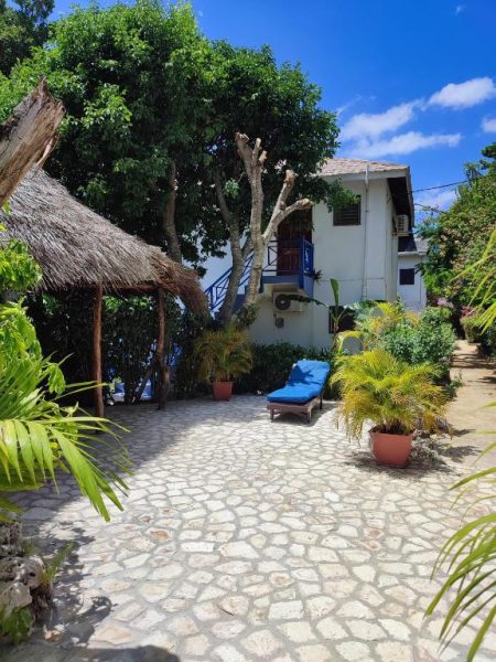 Terraza de piedra con tumbonas y jardín tropical del hotel Ltu Garden con cabaña de palapa