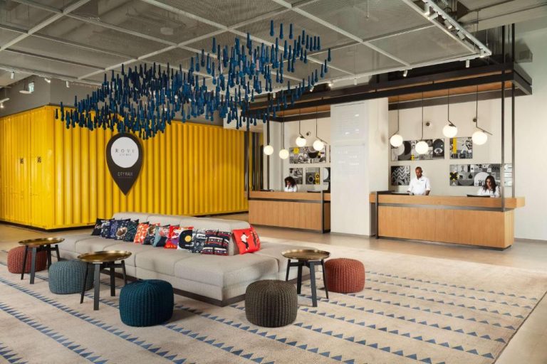 Lobby moderno con recepción y decoración industrial del hotel Rove City Walk en Dubái