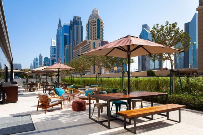 Terraza exterior con mesas y sombrillas del Rove City Walk con vistas al skyline de Dubái