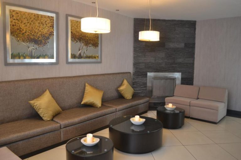Sala de estar con sofás y chimenea en el lobby del Hotel Jose Antonio, decoración moderna y elegante