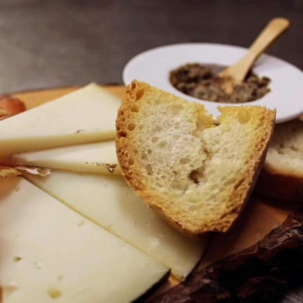 Tabla de quesos artesanales con pan rústico y tapenade en el restaurante del Cortona Resort & Spa