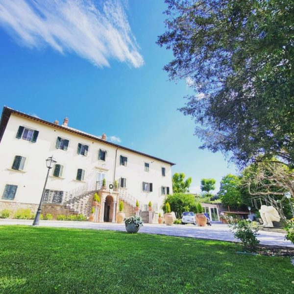 Fachada exterior de la villa histórica del Cortona Resort & Spa rodeada de jardines verdes en la Toscana