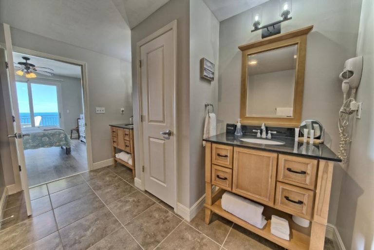 Baño amplio con doble vanidad de madera y encimera de granito en Ocean Front Condo con vistas al mar