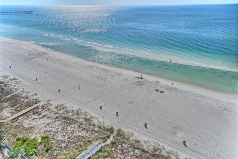 Vista aérea de la playa con aguas turquesas frente al Ocean Front Condo, con muelle al fondo