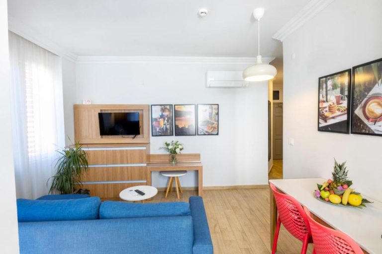 Salón comedor moderno con sofá azul y mesa de frutas en Comfort Suites