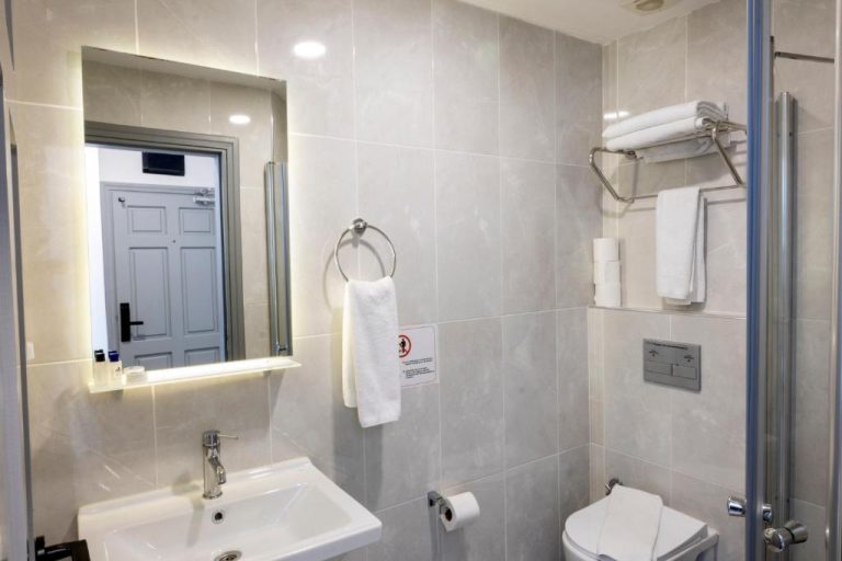 Baño moderno con ducha, lavabo y toallas blancas del Comfort Suites