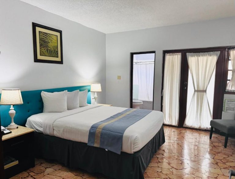 Habitación con cama king size y cabecero turquesa en Toby's Resort, con acceso a baño y terraza