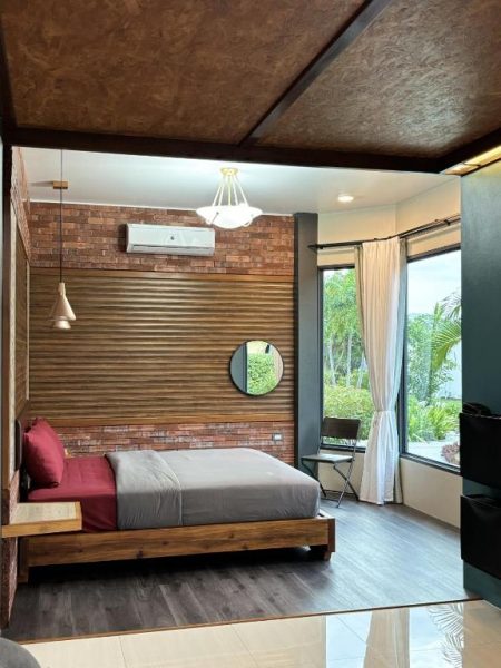 Habitación doble con cama y pared de ladrillo visto en Cafe'@luv22, con ventana y aire acondicionado