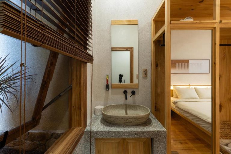 Baño con lavabo de piedra y madera natural en MăngDiang Boutique Hotel con vista a la habitación doble