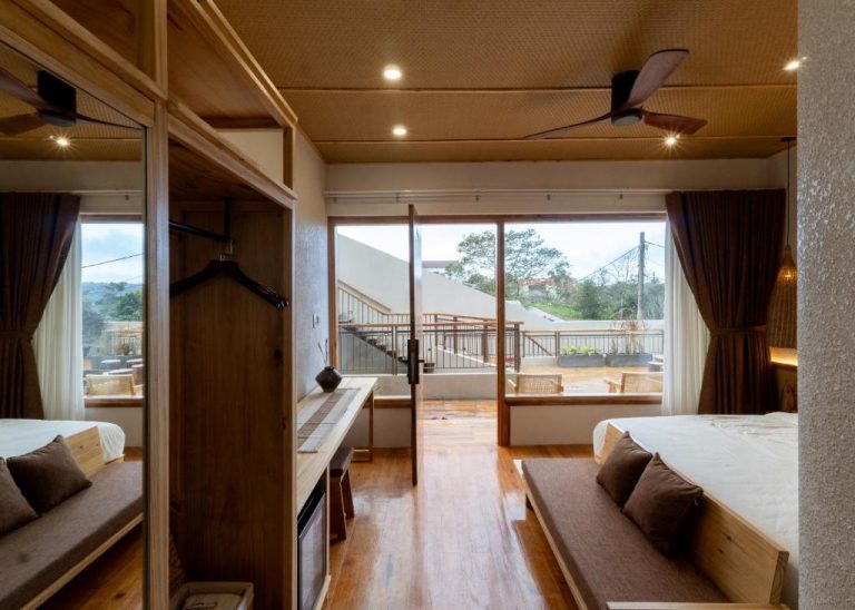 Habitación con suelo de madera, cama doble y terraza con vistas exteriores en MăngDiang Boutique Hotel
