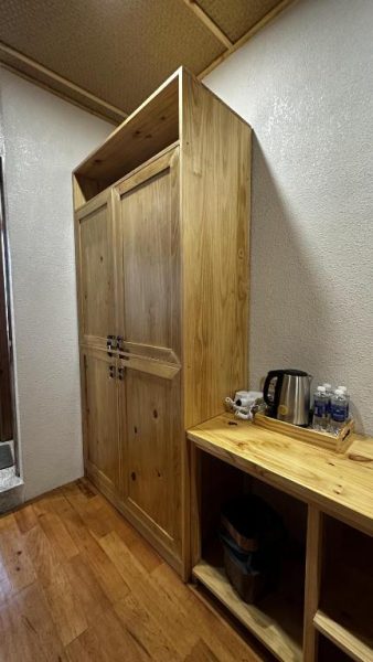 Armario de madera maciza y escritorio con hervidor de agua en habitación del MăngDiang Boutique Hotel