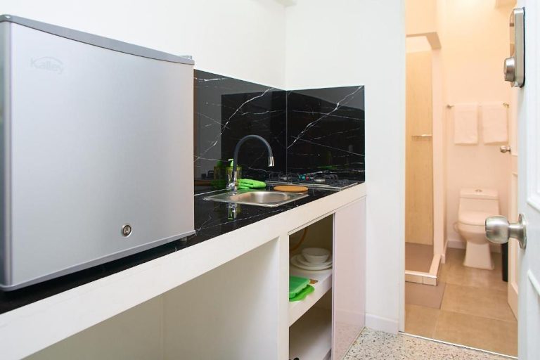 Cocina equipada con nevera, fregadero y encimera de mármol negro en Hotel Boutique Fiorentina Medellín