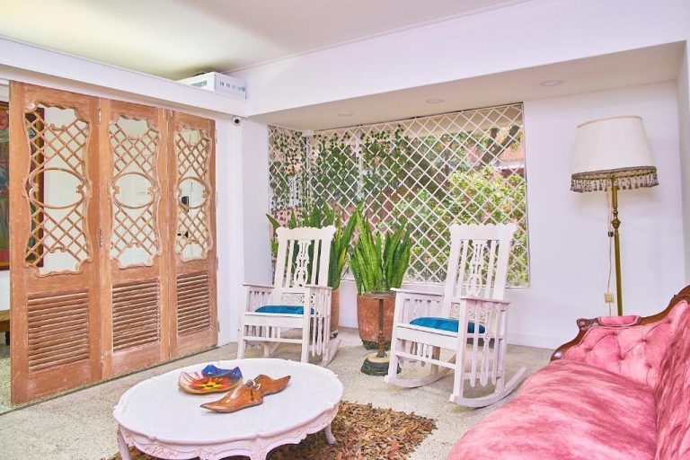 Sala de estar colonial con mecedoras blancas y sofá rosa en Hotel Boutique Fiorentina Medellín