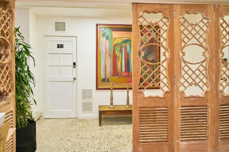Corredor decorado con arte y puerta de habitación 106 en Hotel Boutique Fiorentina Medellín