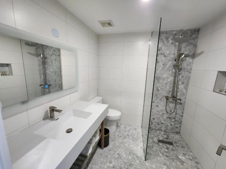 Baño moderno con ducha de lluvia y mosaico hexagonal en el Hotel 39 Jamaica