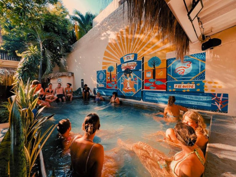 Huéspedes disfrutando de la piscina con colorido mural artístico en Viajero Cartagena Centro Hostel