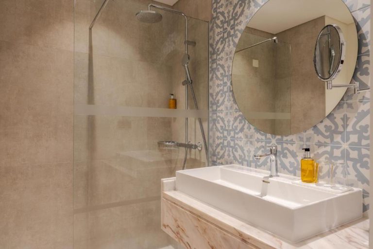 Baño moderno con ducha de lluvia, lavabo sobre encimera de mármol y azulejos decorativos en Sentido Galosol