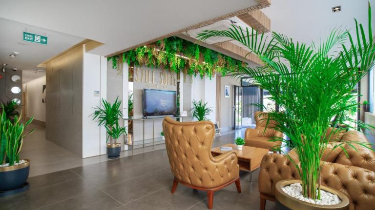 Elegante lobby del Stile Suite Marine Hotel con sillones de cuero y plantas tropicales decorativas