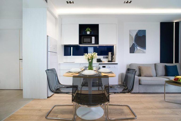 Salón comedor con cocina integrada y mesa para cuatro personas en Stile Suite Marine Hotel