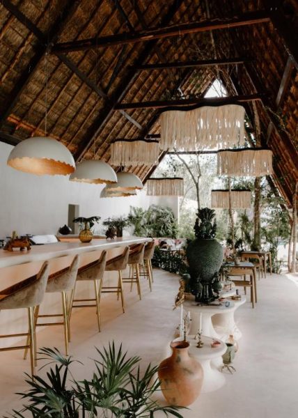 Bar restaurante con techo de palapa y decoración tropical bohemia en Hotel Milam