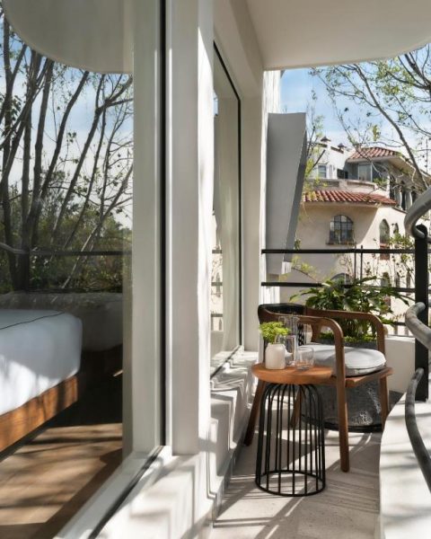 Terraza privada con mesa y silla de madera en el Kimpton Virgilio Polanco con vistas al jardín