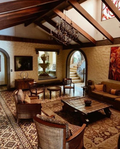 Elegante sala colonial con vigas de madera y araña de hierro forjado en Hotel 1915 Inn & Suites
