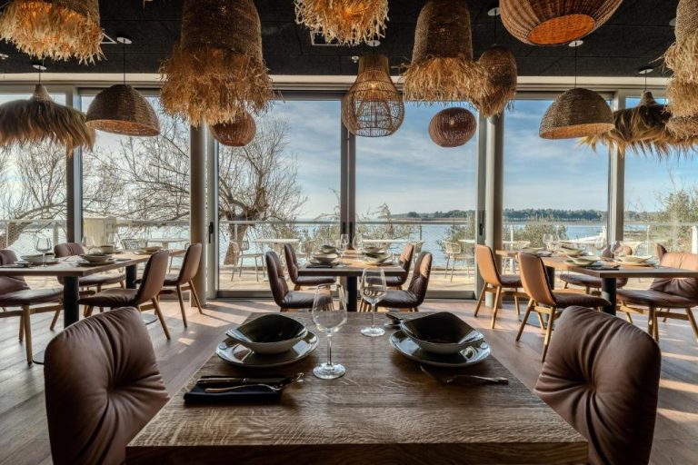 Restaurante del Blu Mare Hotel con mesas de madera, lámparas de mimbre y vistas panorámicas al mar