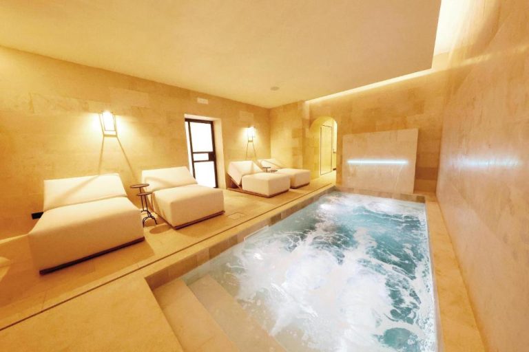 Jacuzzi interior con tumbonas blancas y ambiente de lujo en Casa Nostra Boutique Hotel & Spa