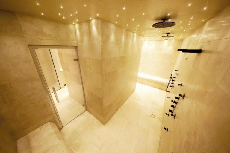 Ducha de lluvia con paneles de hidromasaje y revestimiento de mármol en el spa de Casa Nostra Boutique Hotel